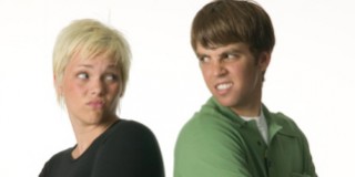 Young man and young woman standing back to back